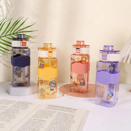 Four colorful water bottles with stickers on a table next to an open book.
