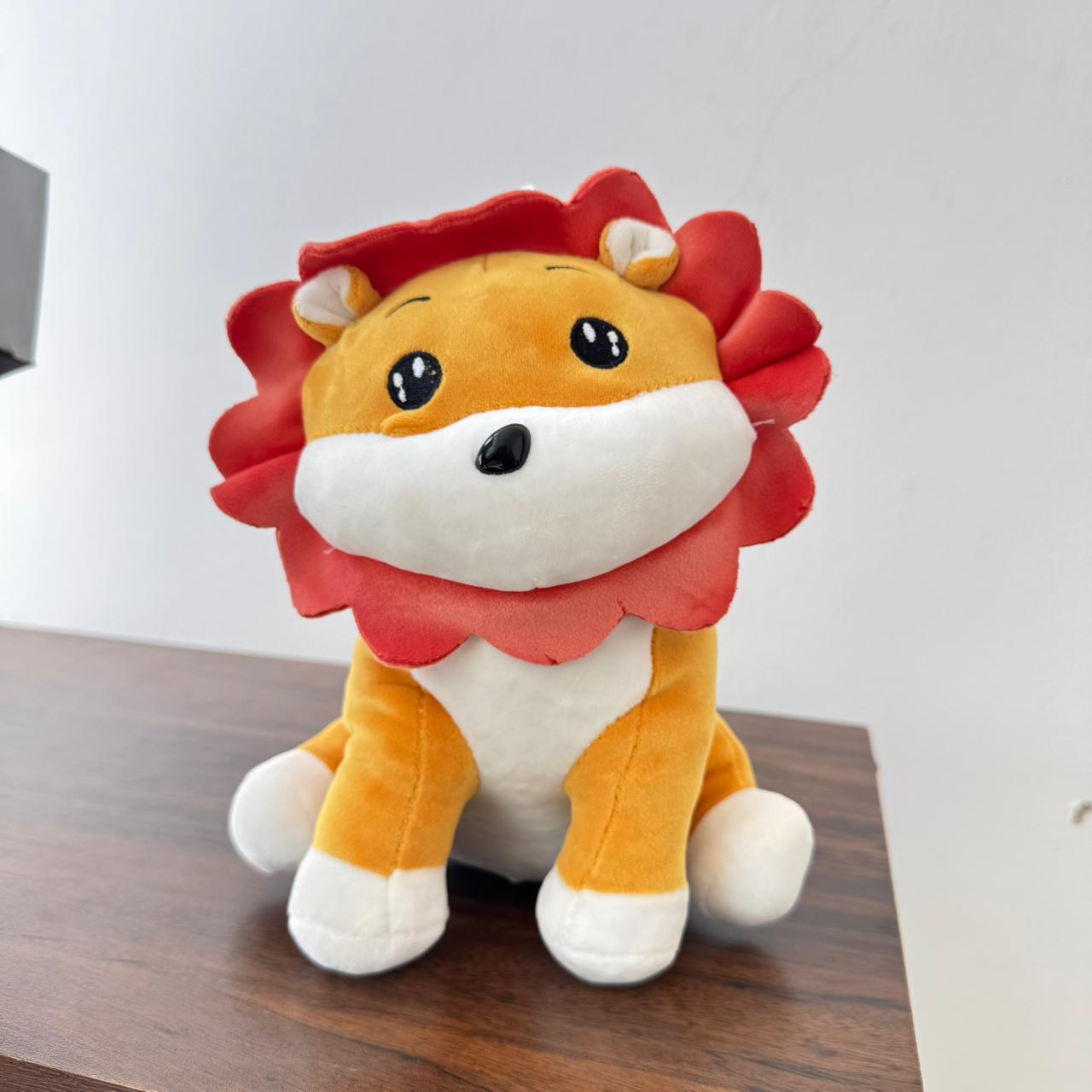 Plush lion toy on a wooden surface with a white background