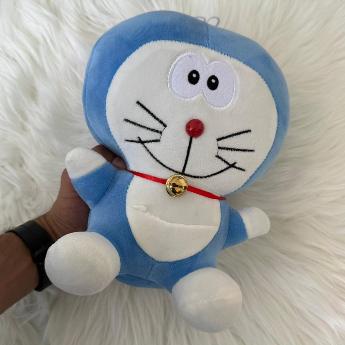 Plush toy resembling a cartoon character held by a hand on a white fluffy background